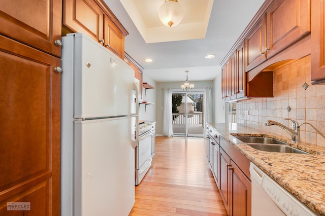 kitchen featuring decorative backsplash, light wood-type flooring, white appliances, sink, and hanging light fixtures