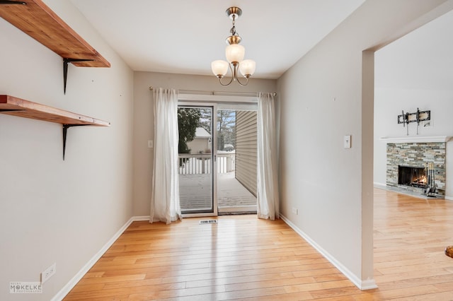 entryway featuring light hardwood / wood-style floors, a stone fireplace, and a chandelier