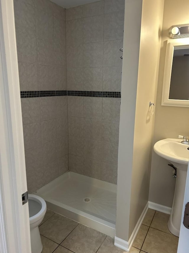 bathroom featuring toilet, tile patterned flooring, and tiled shower