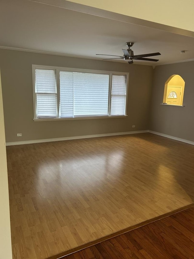 spare room featuring a healthy amount of sunlight, ceiling fan, wood-type flooring, and ornamental molding