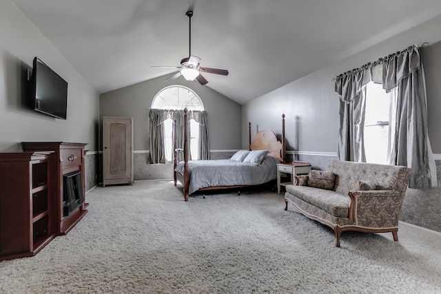 carpeted bedroom with ceiling fan, multiple windows, and vaulted ceiling