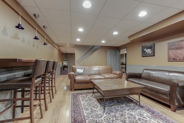 living room featuring a drop ceiling and light wood-type flooring