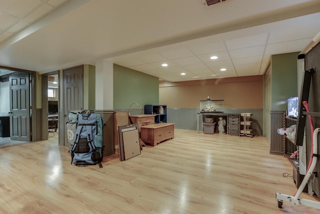 interior space with a paneled ceiling and light hardwood / wood-style flooring