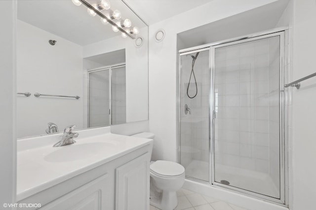 bathroom featuring tile patterned floors, vanity, toilet, and a shower with door