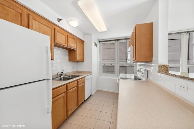 kitchen featuring decorative backsplash, sink, light tile patterned floors, and white appliances