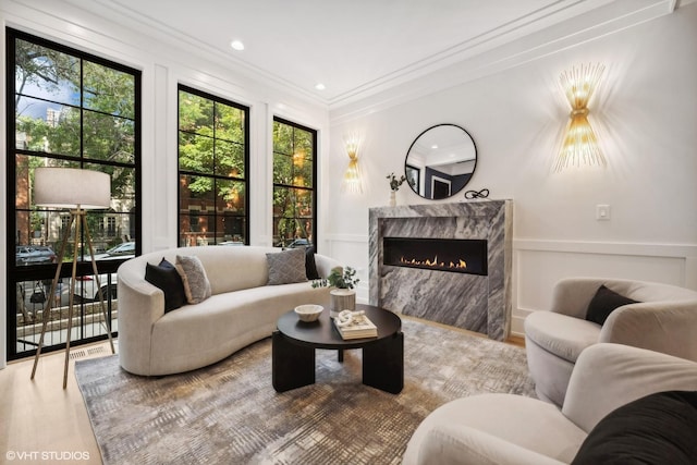 living room with a premium fireplace, hardwood / wood-style floors, and ornamental molding