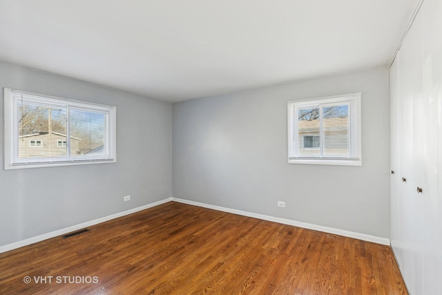 spare room featuring a healthy amount of sunlight and hardwood / wood-style flooring