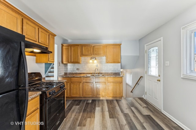 kitchen featuring backsplash, sink, black appliances, stone countertops, and dark hardwood / wood-style floors