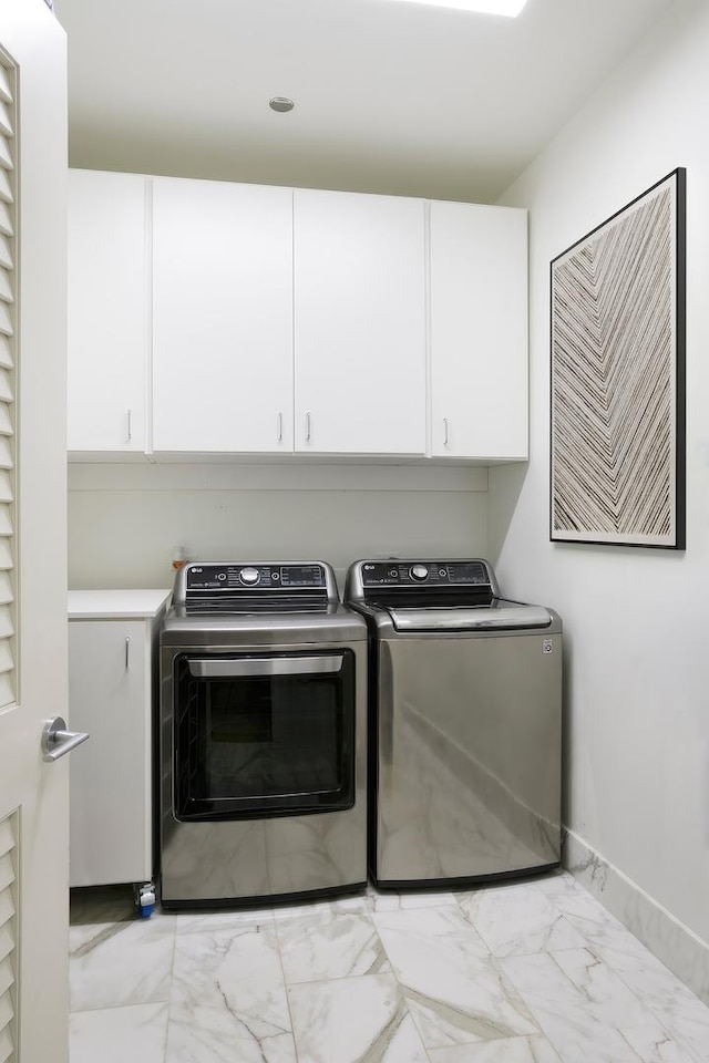 clothes washing area with cabinets and washing machine and clothes dryer