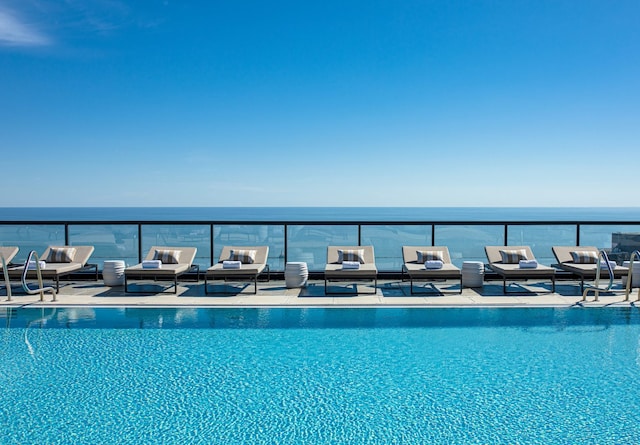 pool with an outdoor hangout area and a water view