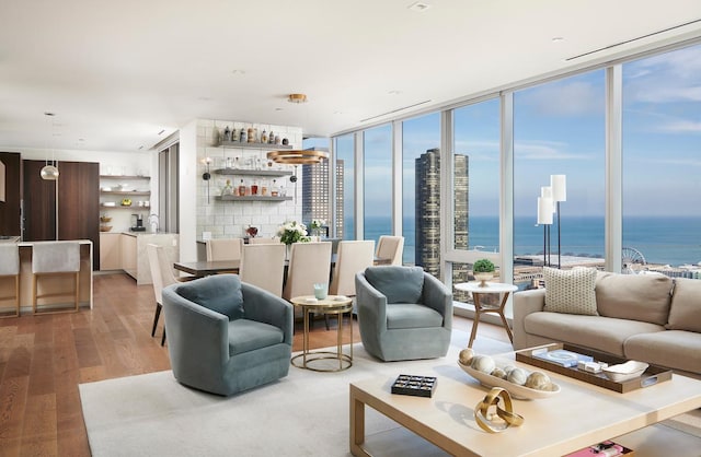 living area with a wealth of natural light, floor to ceiling windows, a water view, and wood finished floors