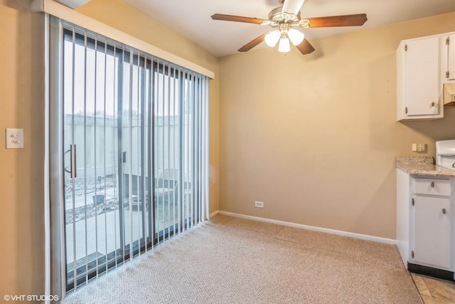 unfurnished dining area with ceiling fan and light carpet