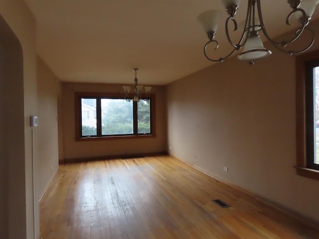 unfurnished dining area with light wood-type flooring and an inviting chandelier