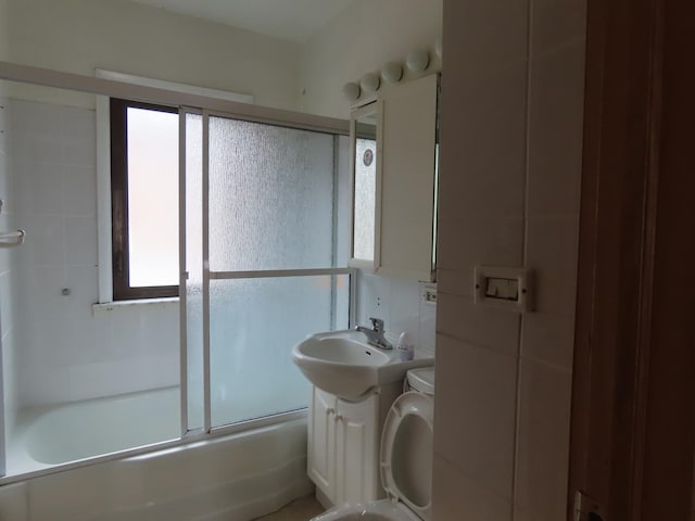 full bathroom featuring combined bath / shower with glass door, backsplash, vanity, tile walls, and toilet