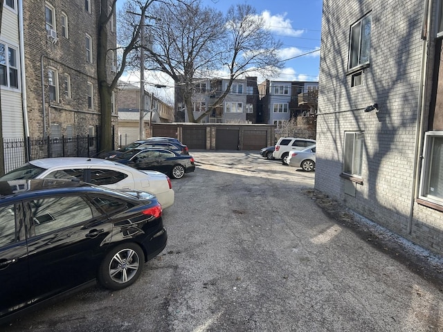 uncovered parking lot featuring a residential view and fence