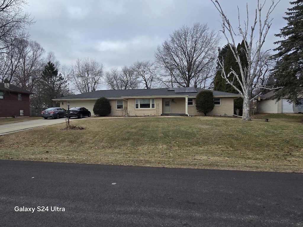 ranch-style house with solar panels, a garage, and a front lawn