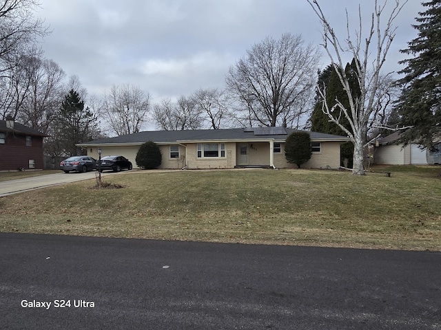 ranch-style house with solar panels, a garage, and a front lawn