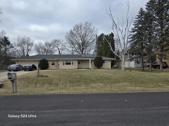 single story home with solar panels, a garage, and a front lawn