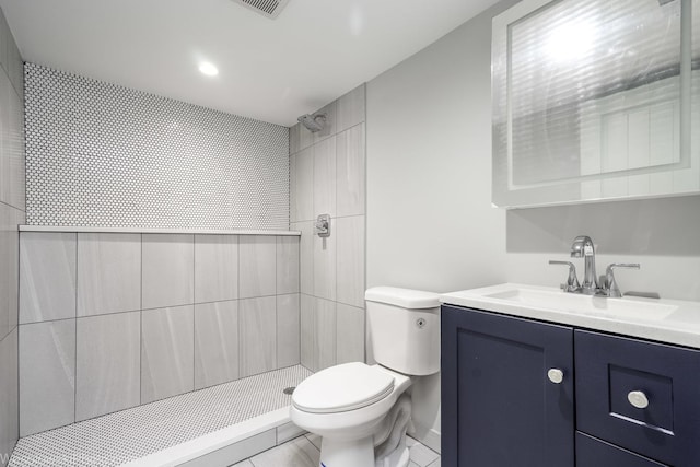 bathroom featuring toilet, vanity, tile patterned floors, and a tile shower