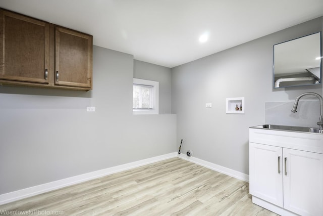 laundry area with cabinets, light hardwood / wood-style flooring, hookup for a washing machine, and sink