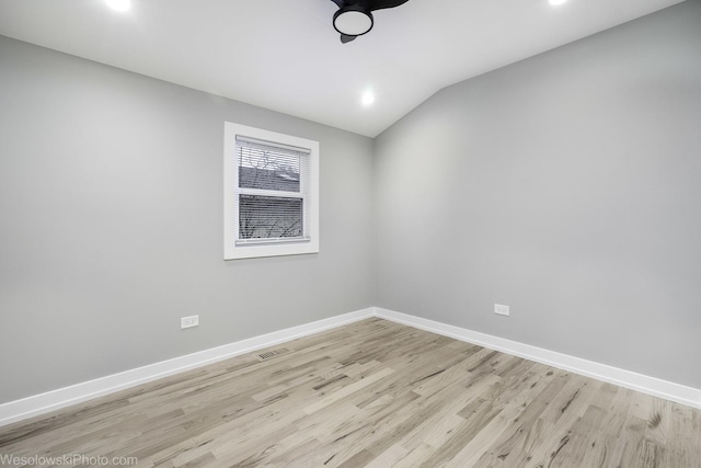 spare room featuring vaulted ceiling and light hardwood / wood-style flooring