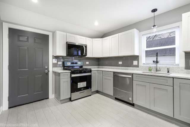 kitchen featuring stainless steel appliances, gray cabinetry, decorative light fixtures, and sink