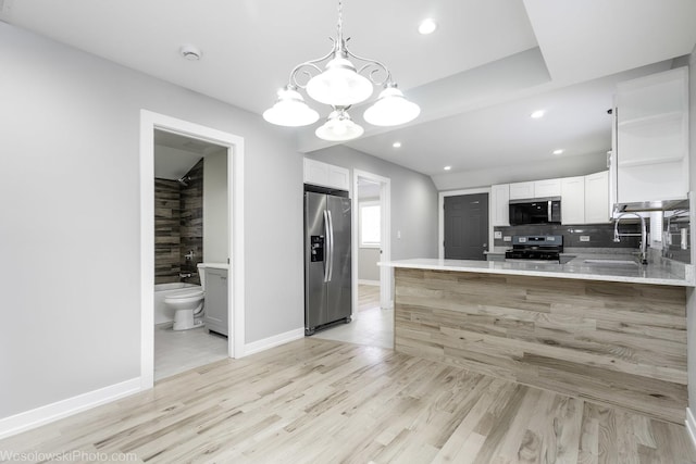 kitchen featuring white cabinetry, kitchen peninsula, stainless steel appliances, pendant lighting, and sink