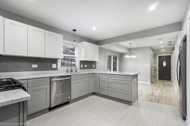 kitchen with black refrigerator, hanging light fixtures, gray cabinets, kitchen peninsula, and stainless steel dishwasher