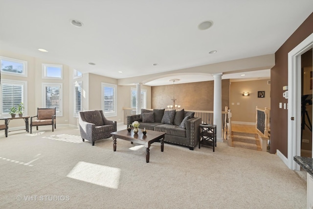 carpeted living room with an inviting chandelier, a healthy amount of sunlight, and ornate columns