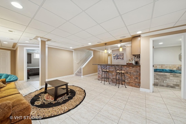 tiled living room with bar, crown molding, and a drop ceiling