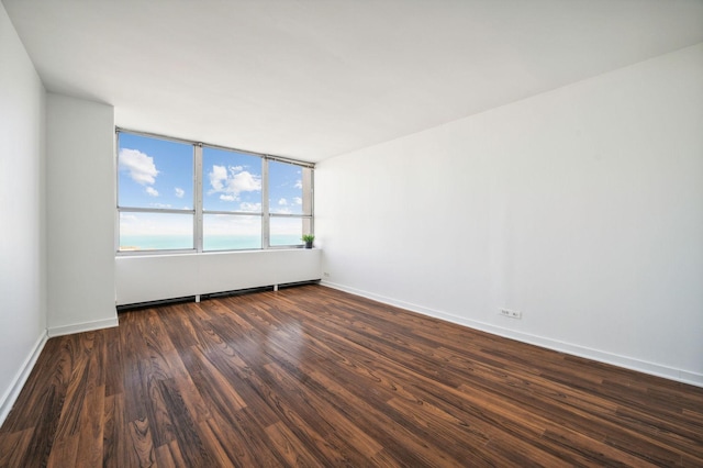 unfurnished room with dark hardwood / wood-style flooring and a water view