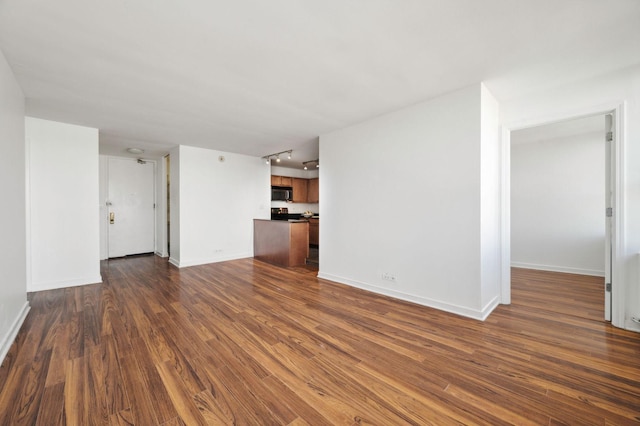 unfurnished living room with rail lighting and dark wood-type flooring