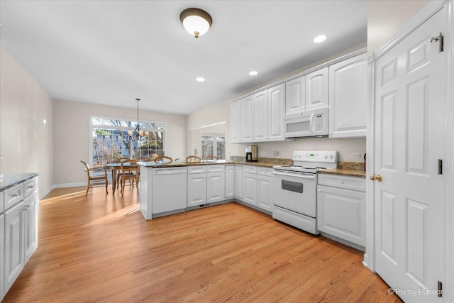 kitchen featuring kitchen peninsula, light wood-type flooring, white appliances, pendant lighting, and white cabinetry