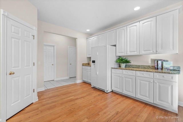 kitchen featuring white cabinets, stone countertops, light wood-type flooring, and white refrigerator with ice dispenser