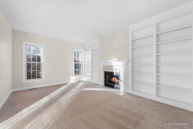 unfurnished living room featuring light carpet, built in features, and a fireplace