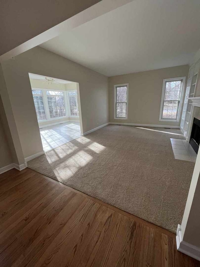 unfurnished living room featuring a tiled fireplace and light colored carpet