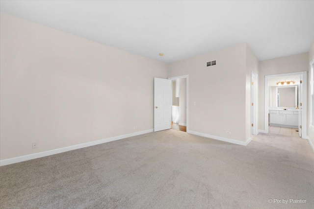 unfurnished bedroom with light carpet and ensuite bath