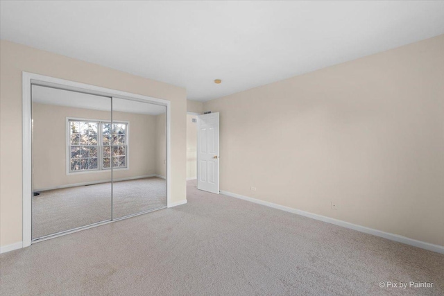 unfurnished bedroom featuring light carpet and a closet