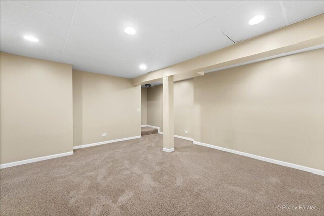 basement featuring a paneled ceiling and carpet floors