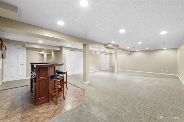 basement featuring dark colored carpet and a paneled ceiling