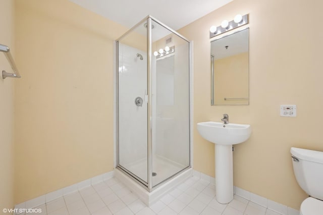 bathroom featuring tile patterned flooring, toilet, and a shower with shower door