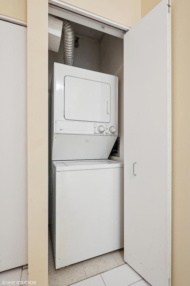 laundry area featuring stacked washer / dryer and light tile patterned floors