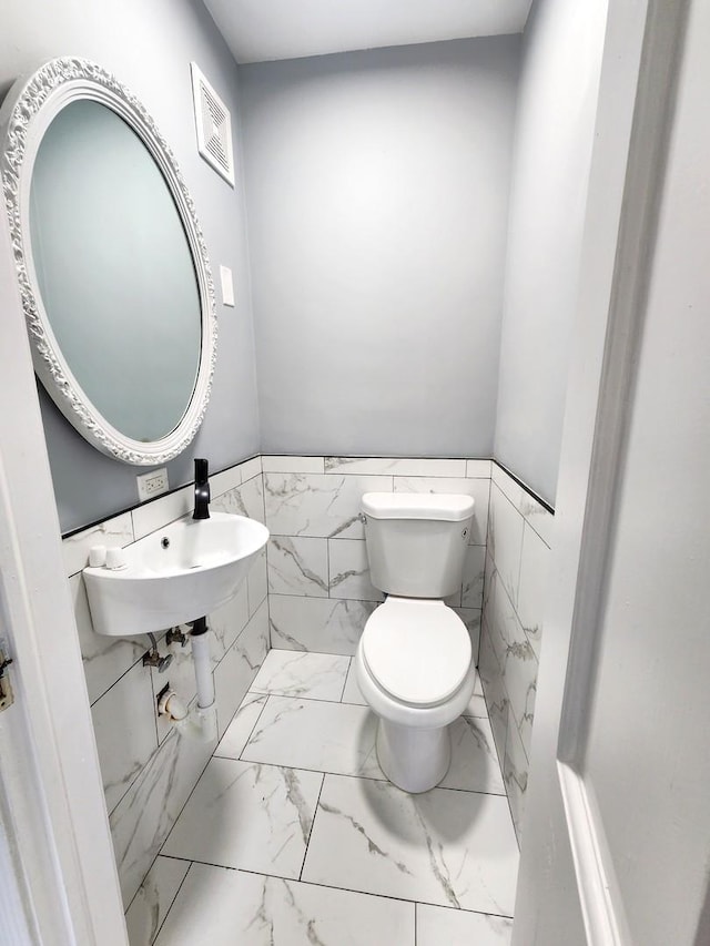 bathroom featuring toilet and tile walls