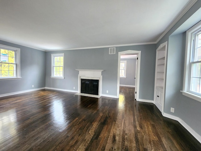 unfurnished living room featuring ornamental molding, dark wood-type flooring, and a wealth of natural light