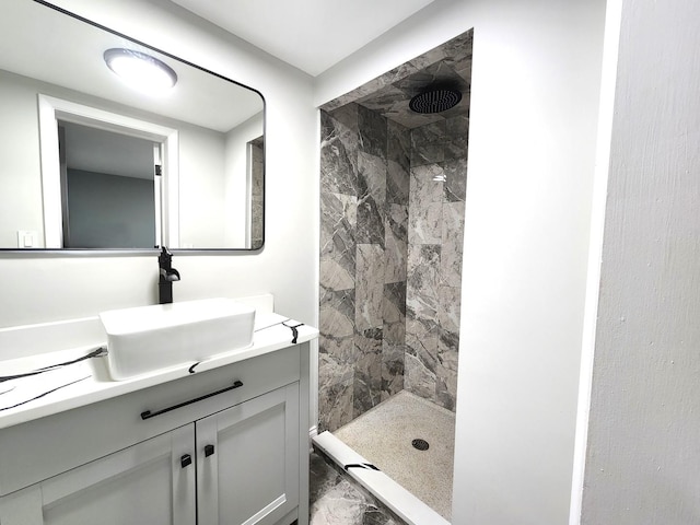 bathroom with tiled shower and vanity