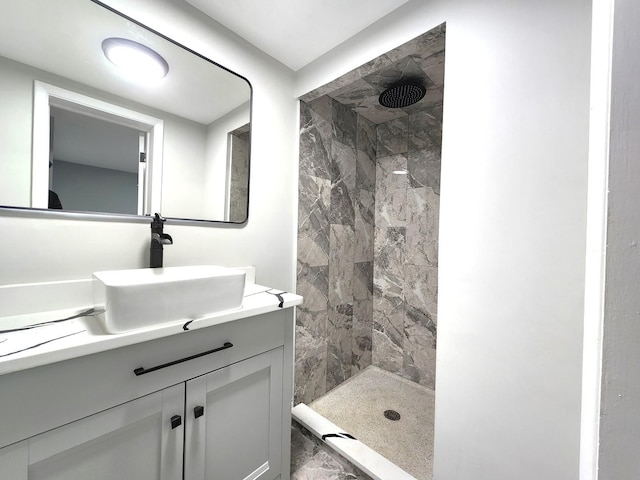 bathroom with a tile shower and vanity