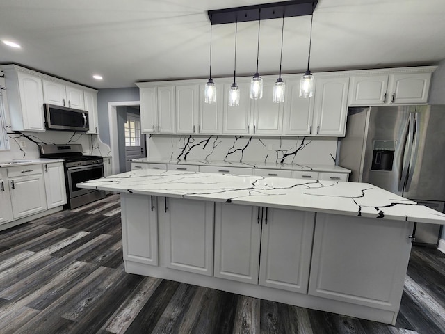 kitchen featuring pendant lighting, a center island, light stone counters, white cabinetry, and stainless steel appliances