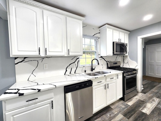 kitchen with sink, light stone counters, dark hardwood / wood-style flooring, white cabinets, and appliances with stainless steel finishes