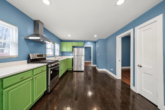 kitchen with sink, wall chimney exhaust hood, green cabinets, dark hardwood / wood-style floors, and appliances with stainless steel finishes