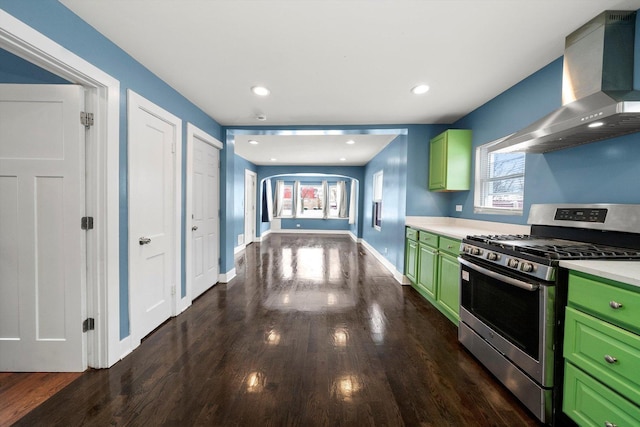 kitchen featuring stainless steel gas range oven, green cabinets, a healthy amount of sunlight, and wall chimney range hood